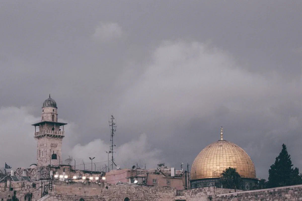 Iconic Dome of the Rock and nearby minaret in overcast Jerusalem skyline.