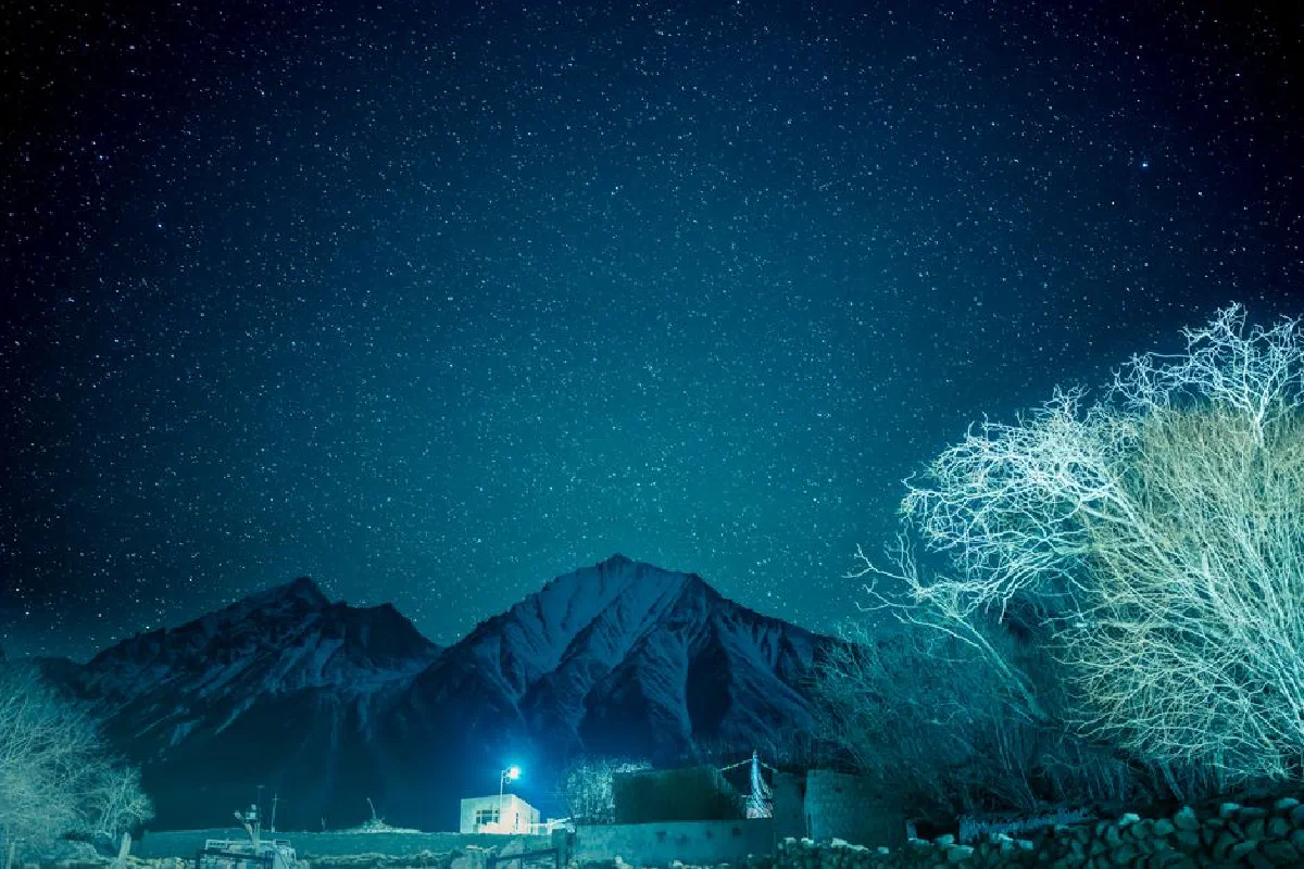 A breathtaking view of the starry sky over the rugged mountains in Ladakh, capturing the serene beauty and mystique of the night.