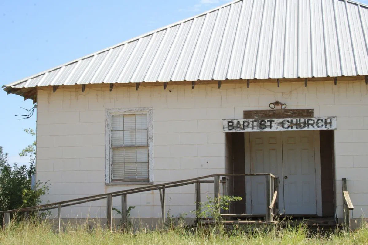An old, white Baptist church with a metal roof and rustic charm.