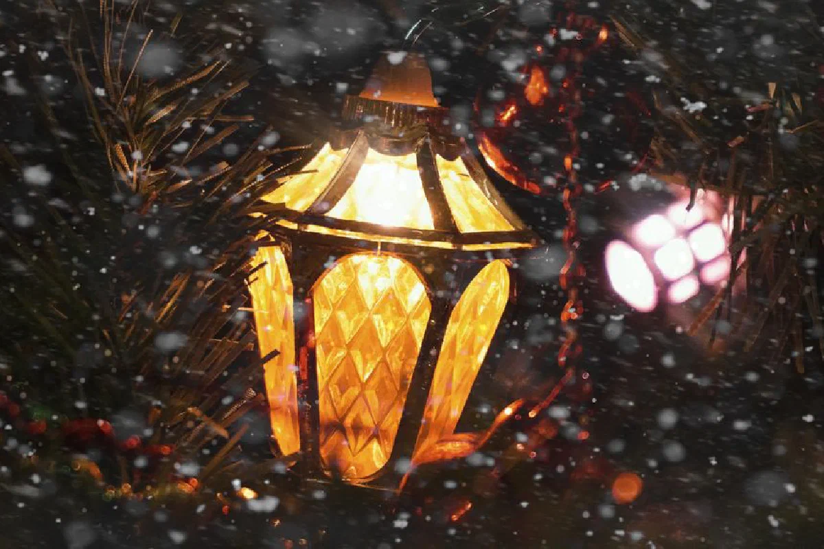 Close-up of an illuminated Christmas lantern surrounded by snowflakes, creating a festive winter mood.