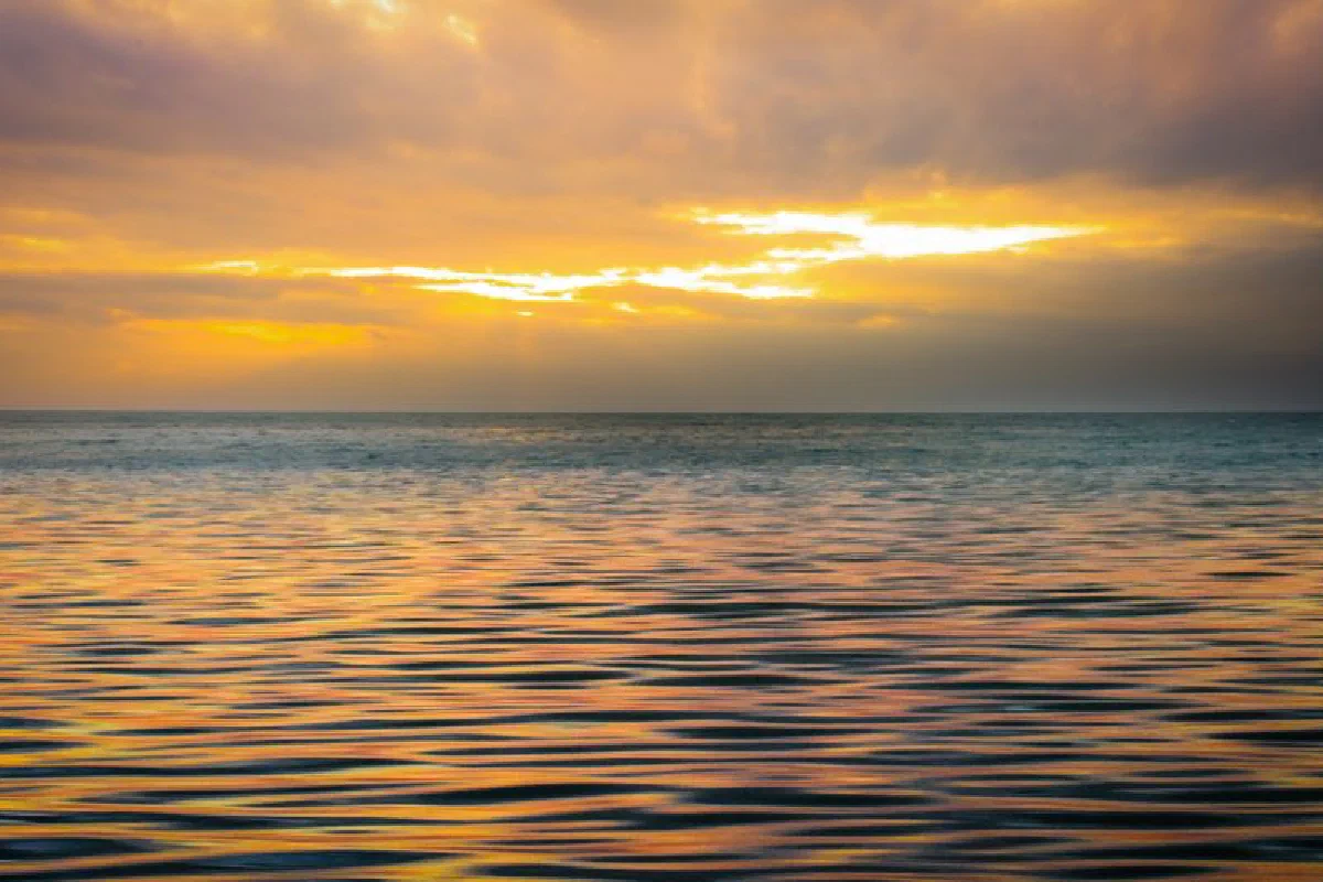 Stunning ocean view capturing the serene sunset with golden hues reflecting off the water's surface.