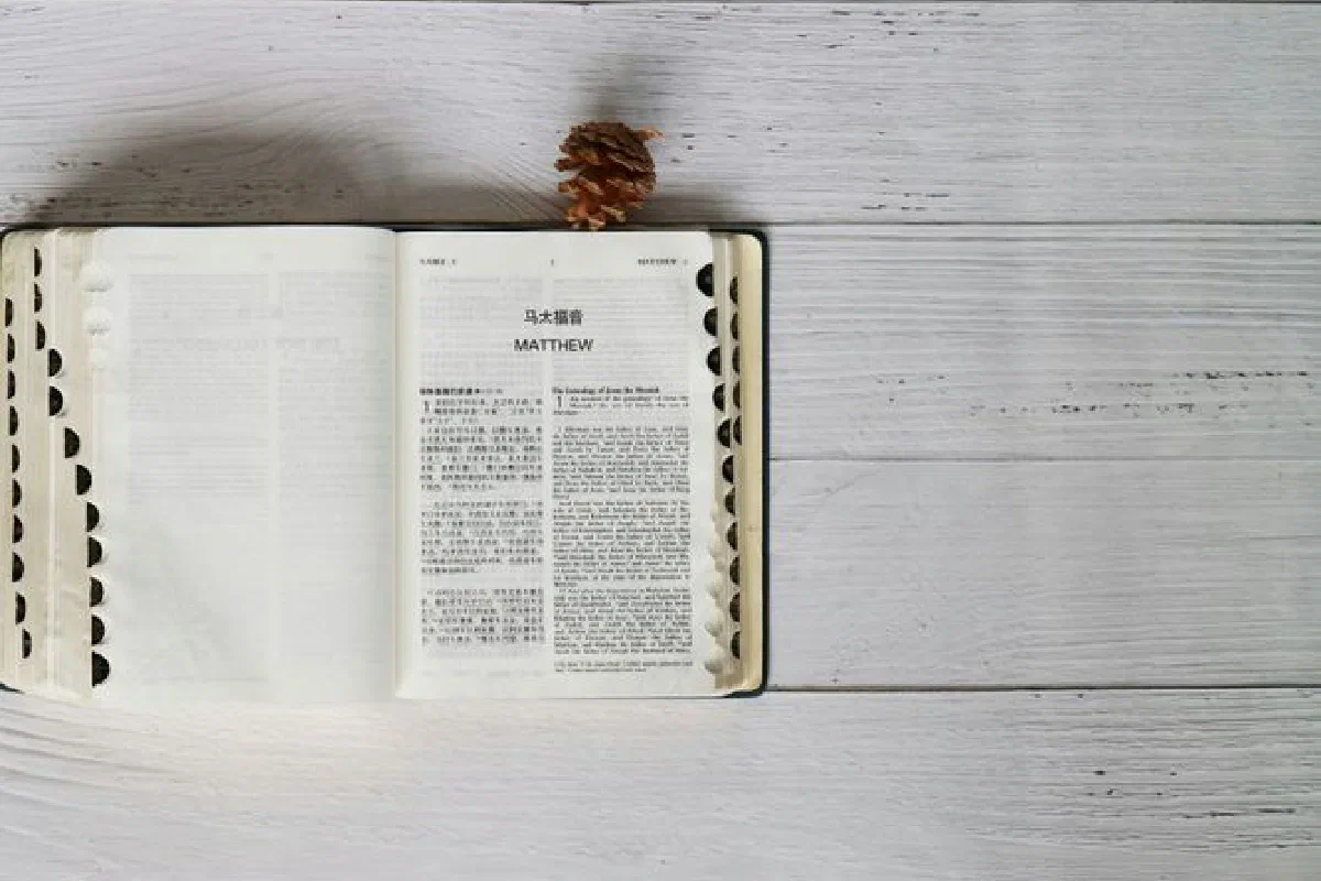 Bible open to Matthew with Mandarin and English text on rustic wood background.