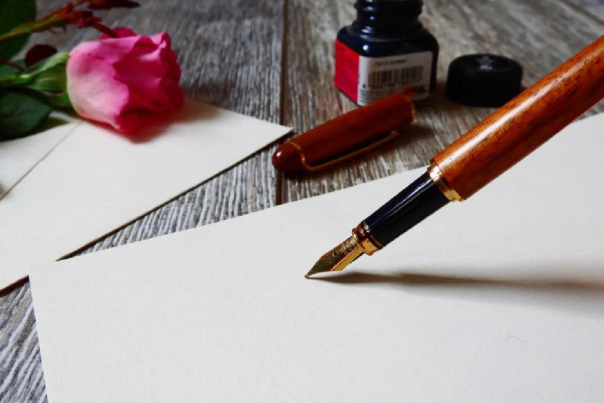 A romantic setup with a rose, fountain pen, and paper, perfect for heartfelt writing.