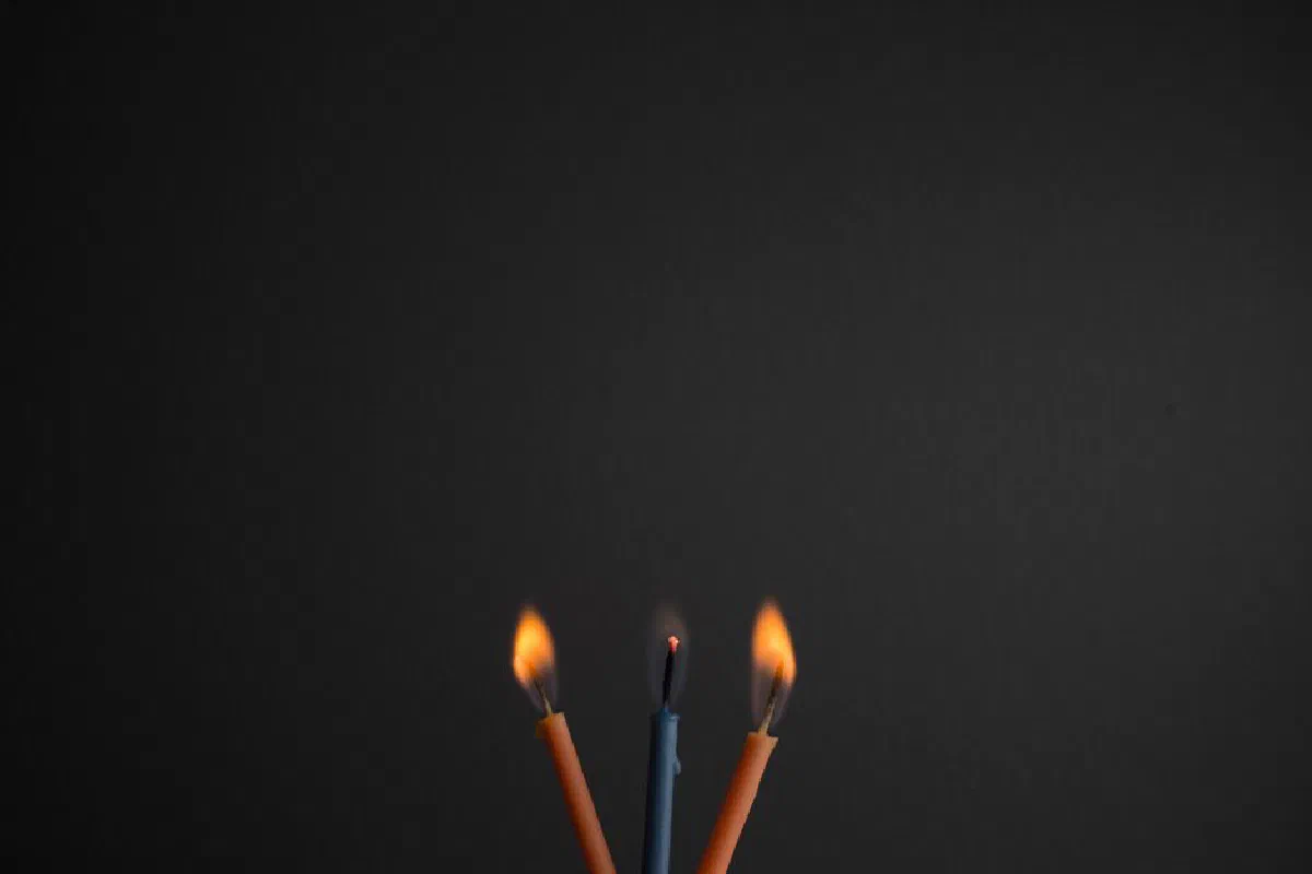 Close-up of three burning candles on a dark background, creating a warm and intimate mood.