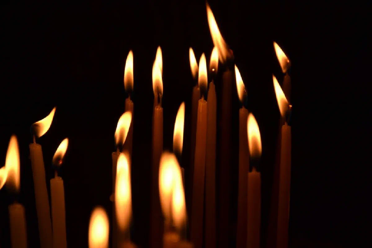 A captivating close-up of lit candles with flames glowing in the dark, creating a warm and serene atmosphere.