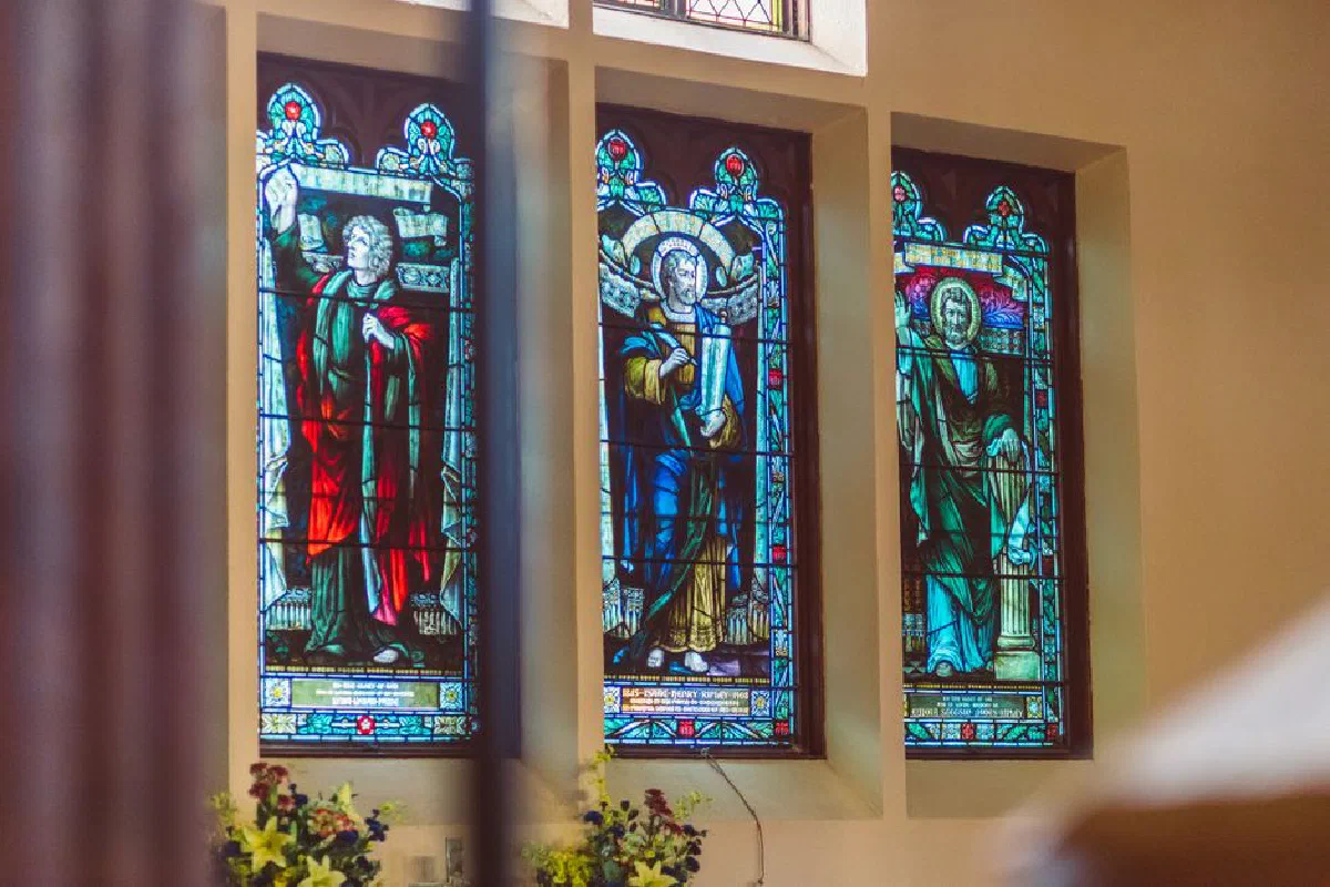Colorful stained glass windows depicting religious figures in a church setting.