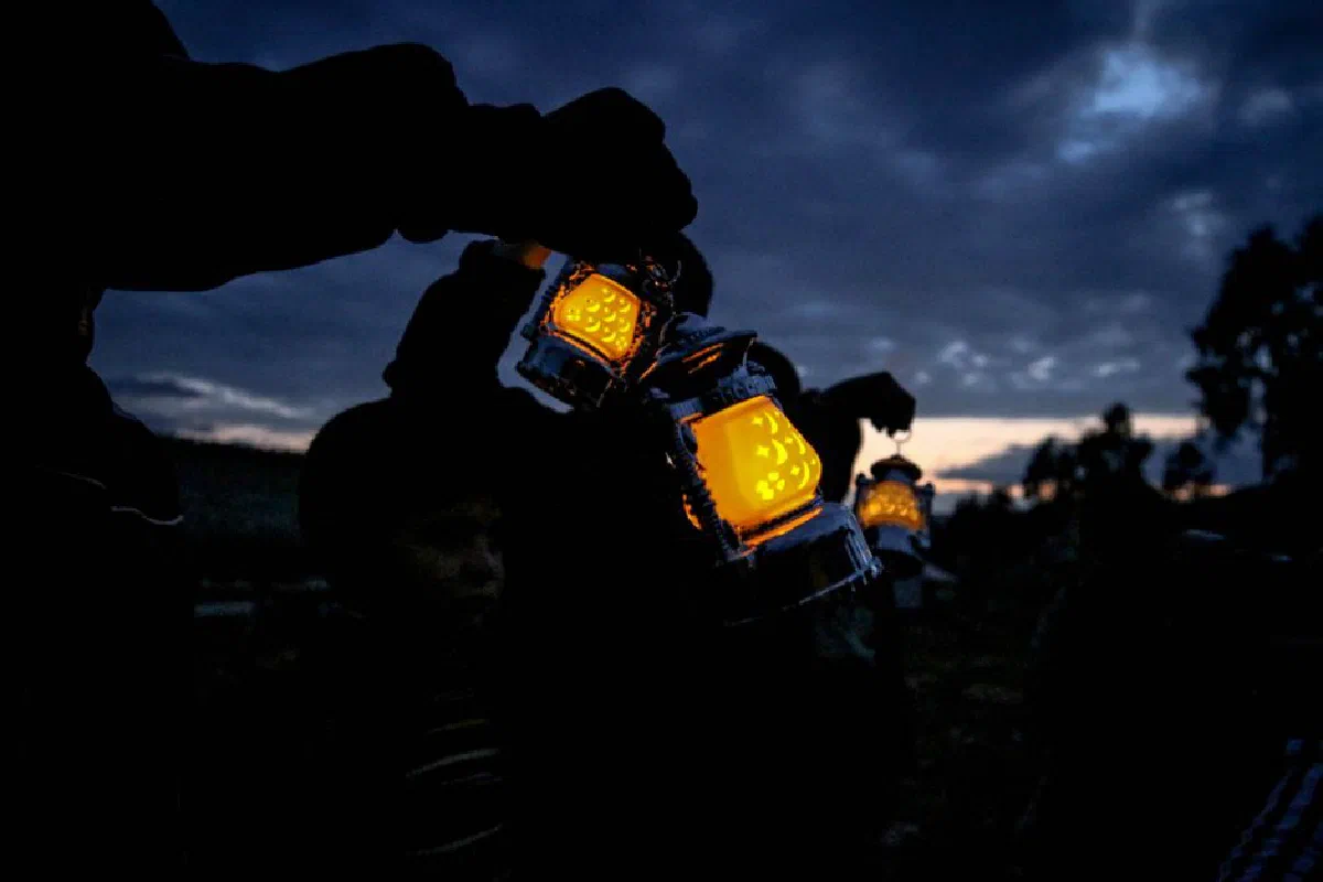 People holding glowing lanterns against the night sky in Idlib, Syria.