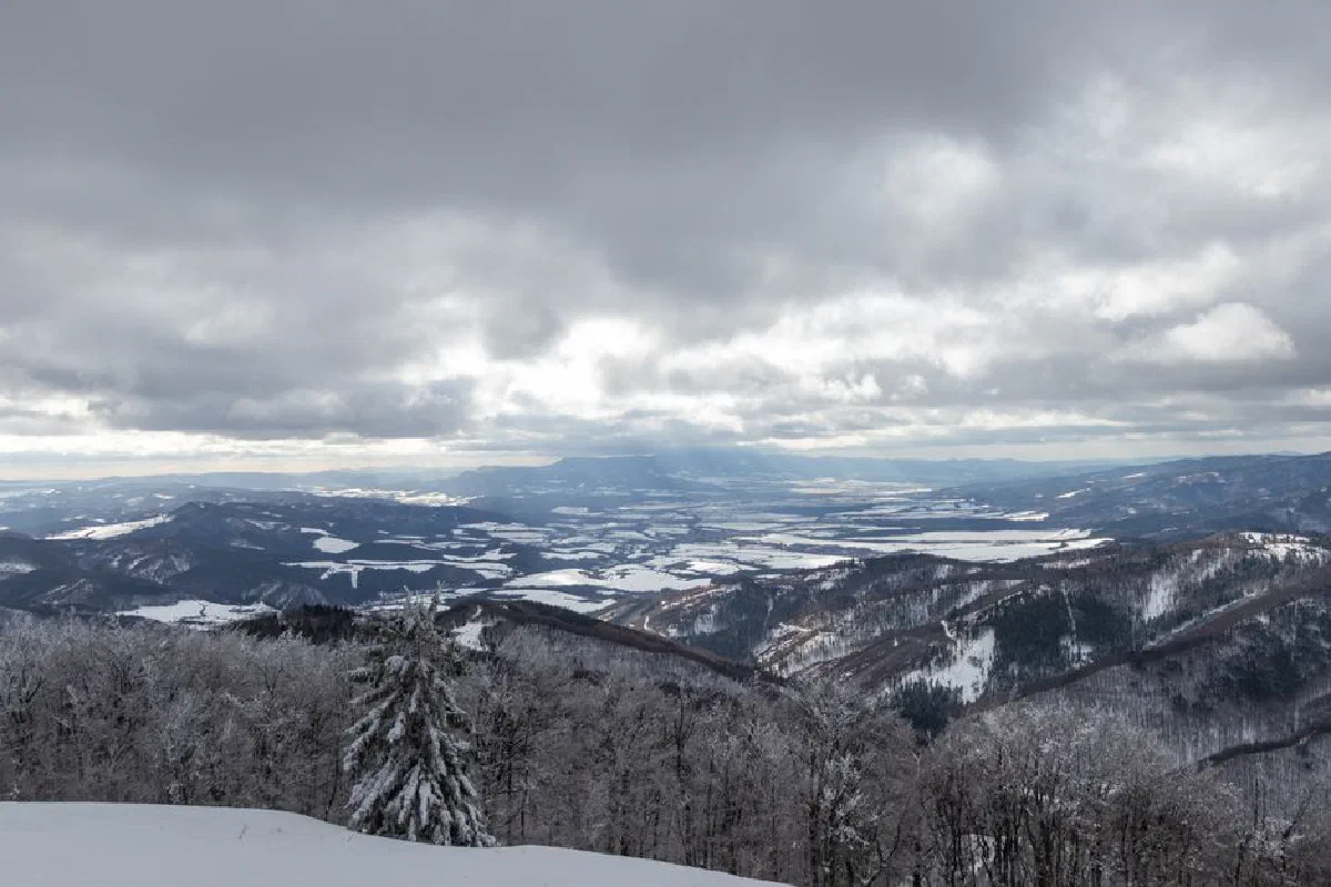 Scenic winter view of snow-covered mountains under a cloudy sky.