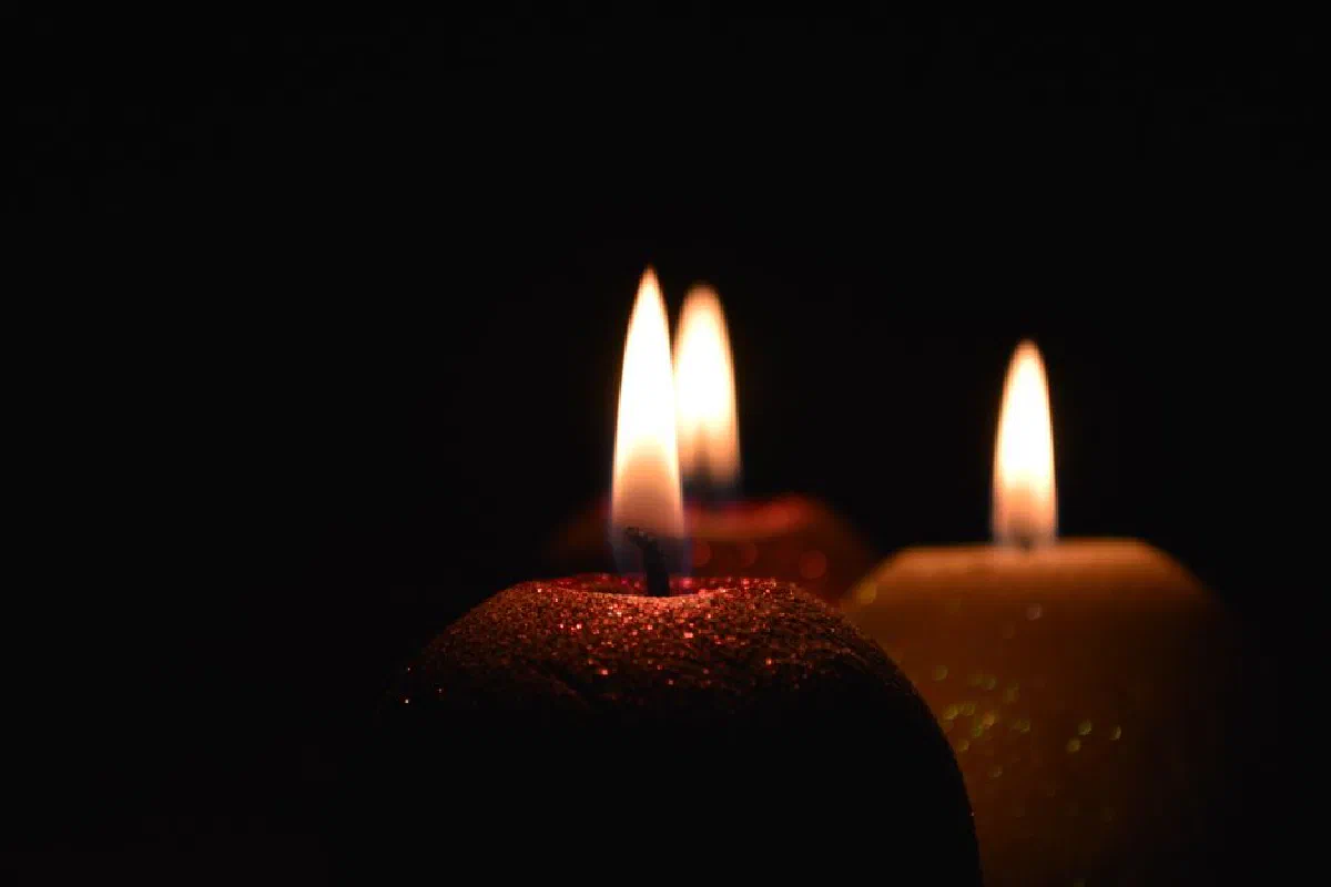 Elegant close-up of three glowing candles casting a warm light in the dark.