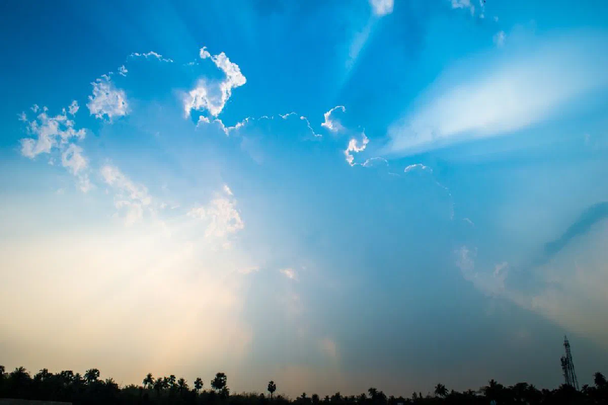 Captivating image of a dramatic cloudscape with sun rays emerging from behind clouds in a clear blue sky.