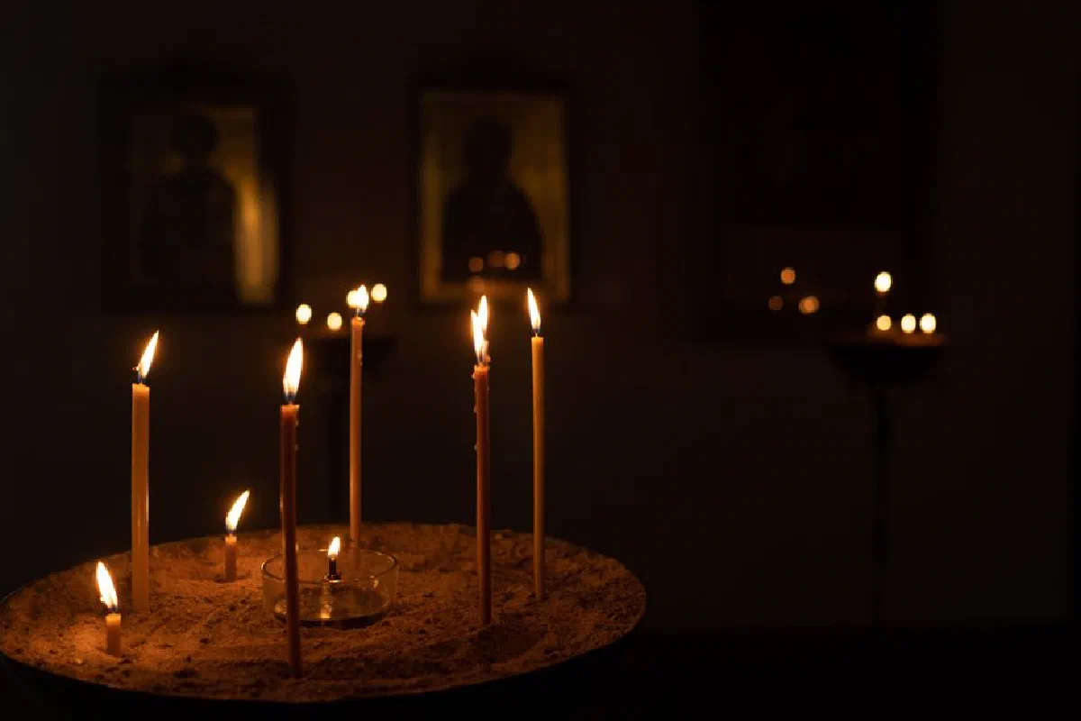 Candles illuminating orthodox icons in a dimly lit church setting, creating a warm atmosphere.