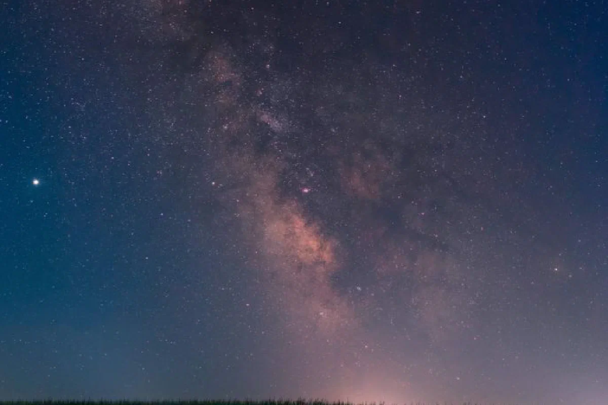 The Milky Way illuminates a clear night sky over a lush field in Antimovo, Bulgaria.