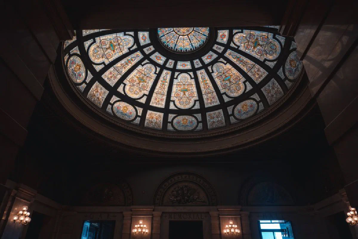 Elegant stained glass dome ceiling with intricate patterns in a dimly lit interior setting.