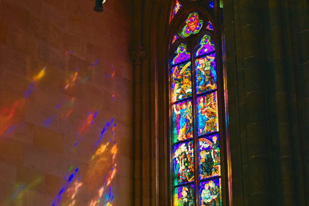 Colorful stained glass window in Prague chapel casting vibrant reflections.