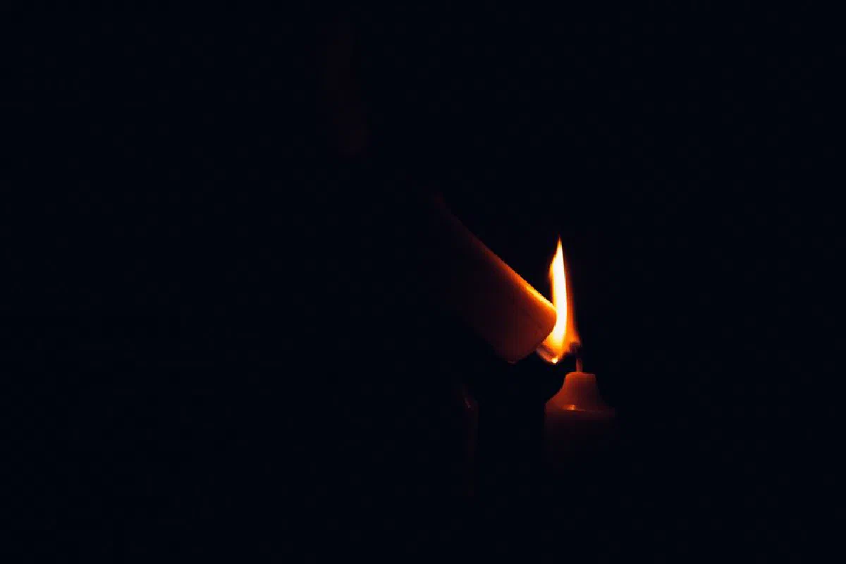 Close-up of a lit candle in darkness, highlighting a serene and mysterious ambiance.