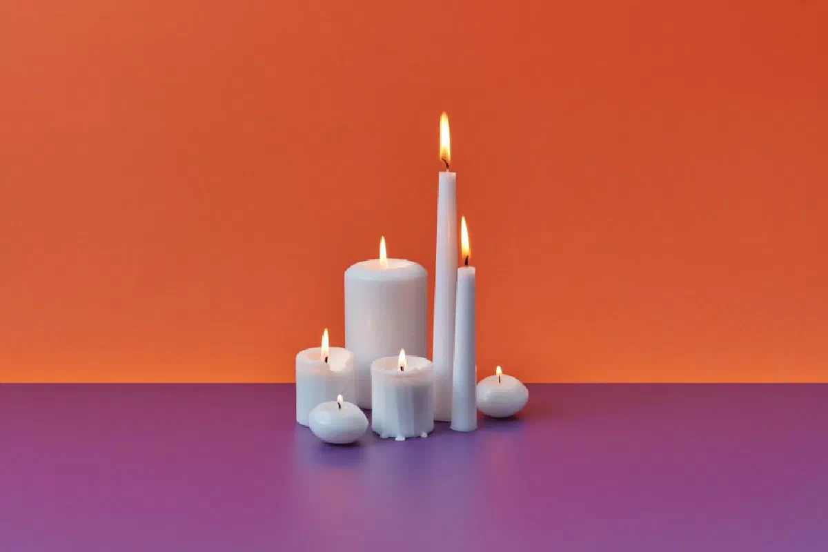 Elegant assortment of lit candles on a colorful gradient background, creating a warm and cozy ambiance.