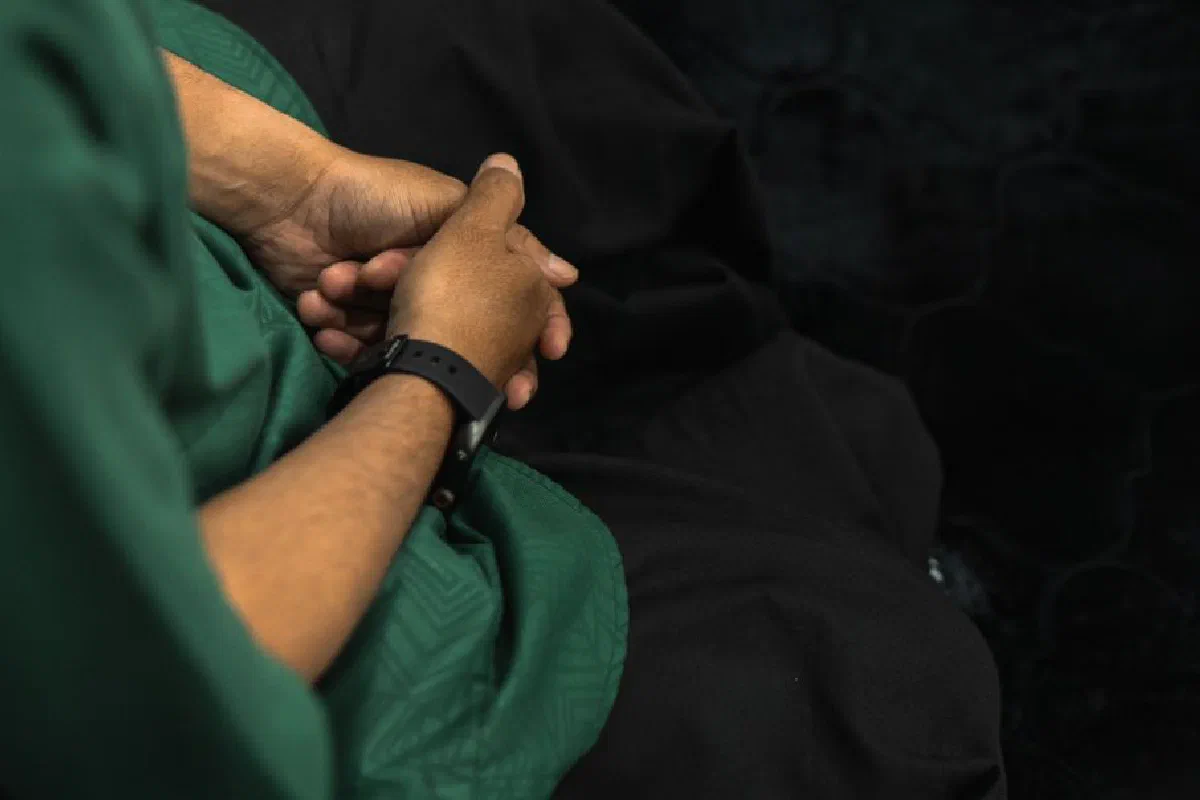 A person in deep contemplation during Islamic prayer, hands folded in a mosque.