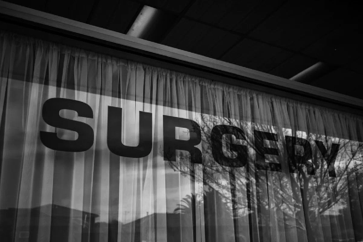 Monochrome image of a surgery sign with curtains and reflections.