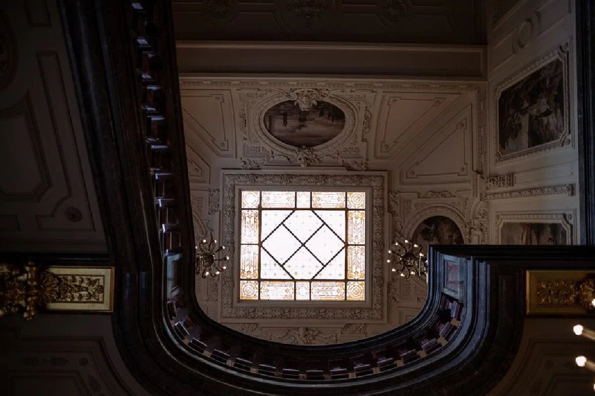 A beautifully decorated ceiling with a stained glass window and intricate moldings.