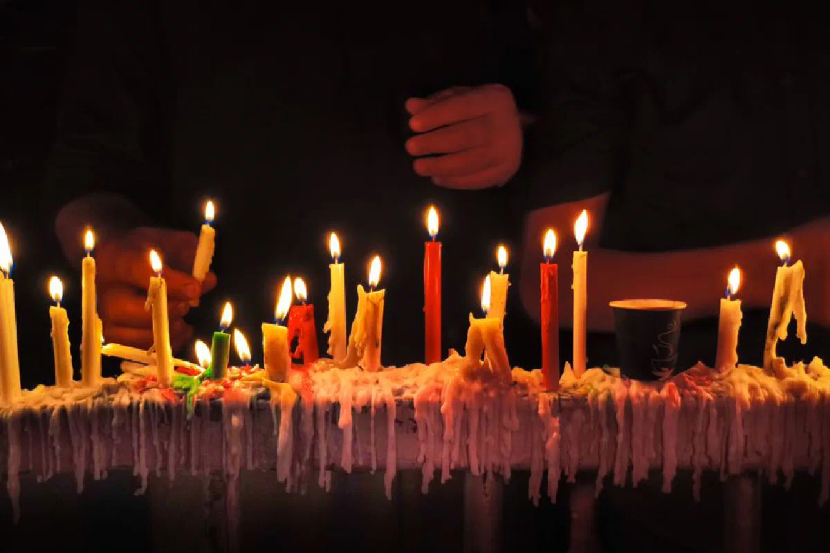Close-up of colorful lit candles on a dark background, creating a warm ambiance.