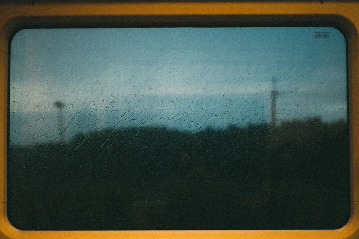 A rainy window view from a train in Tallinn, Estonia, capturing an atmospheric and moody landscape.