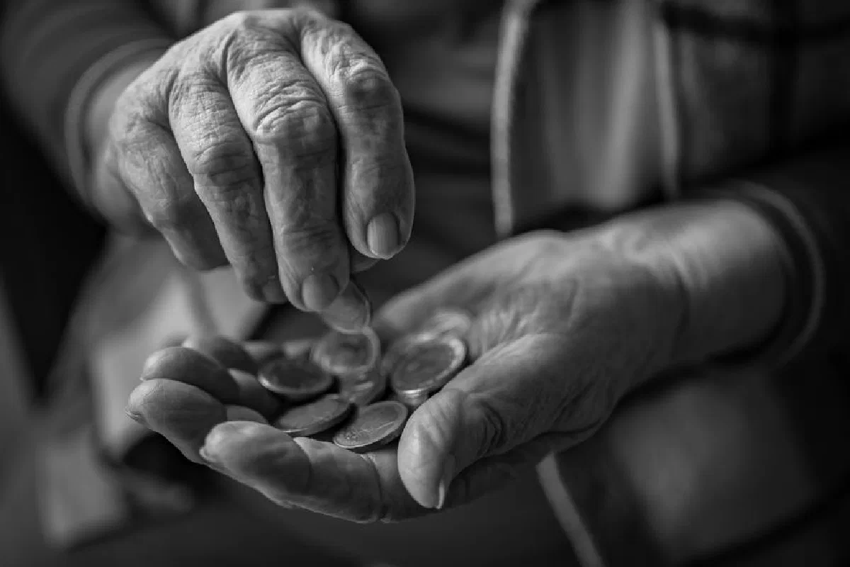A close-up of elderly hands counting coins, portraying poverty and financial insecurity.