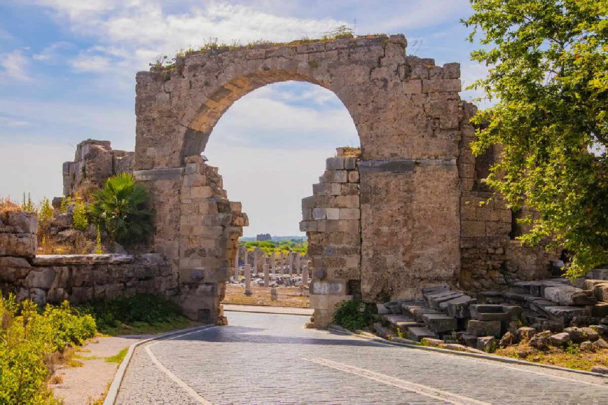 Explore the ancient Roman arch in Side, Turkey, showcasing historical ruins under a sunny sky.