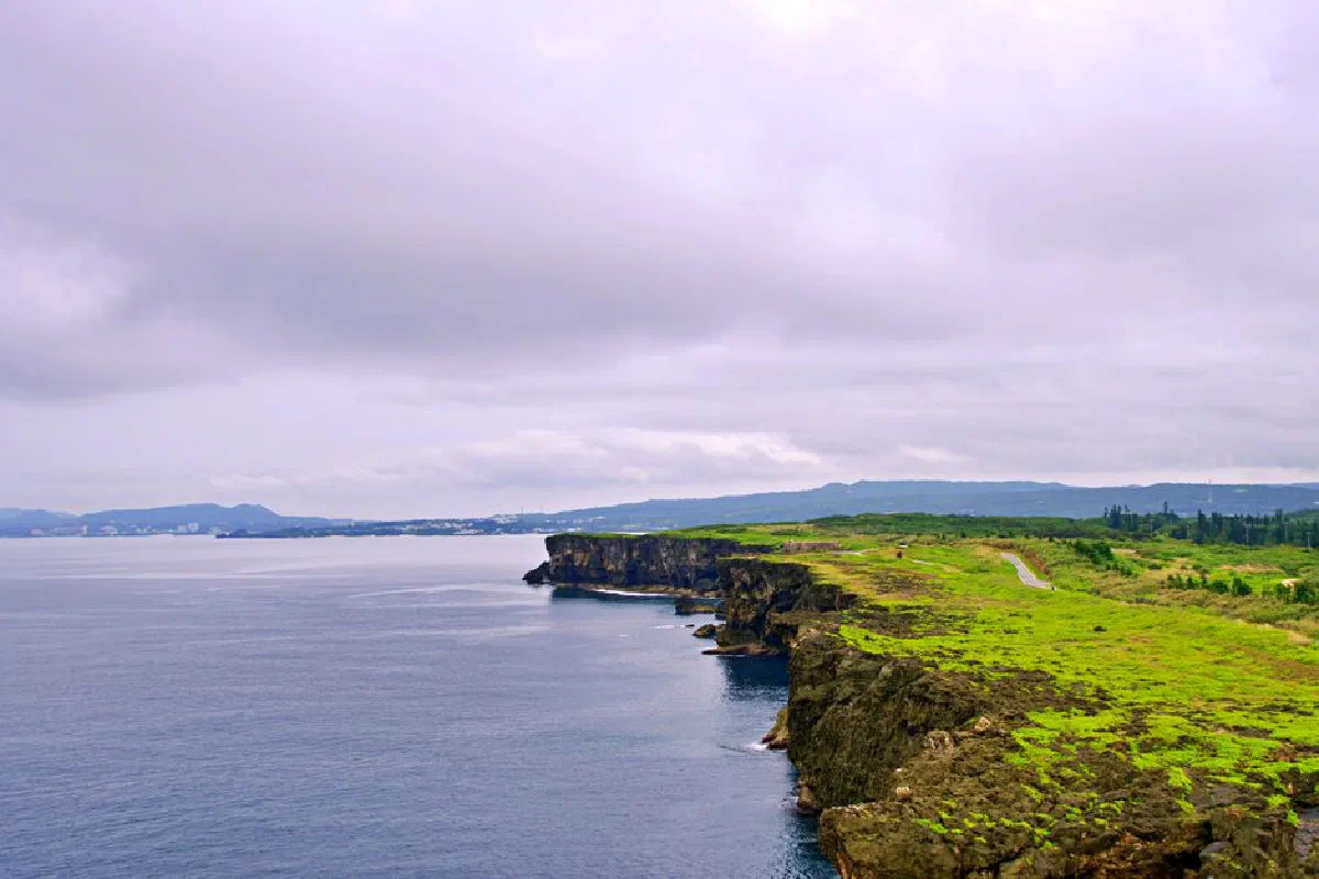 Explore the breathtaking coastal cliffs of Okinawa, showcasing lush greenery and the ocean.