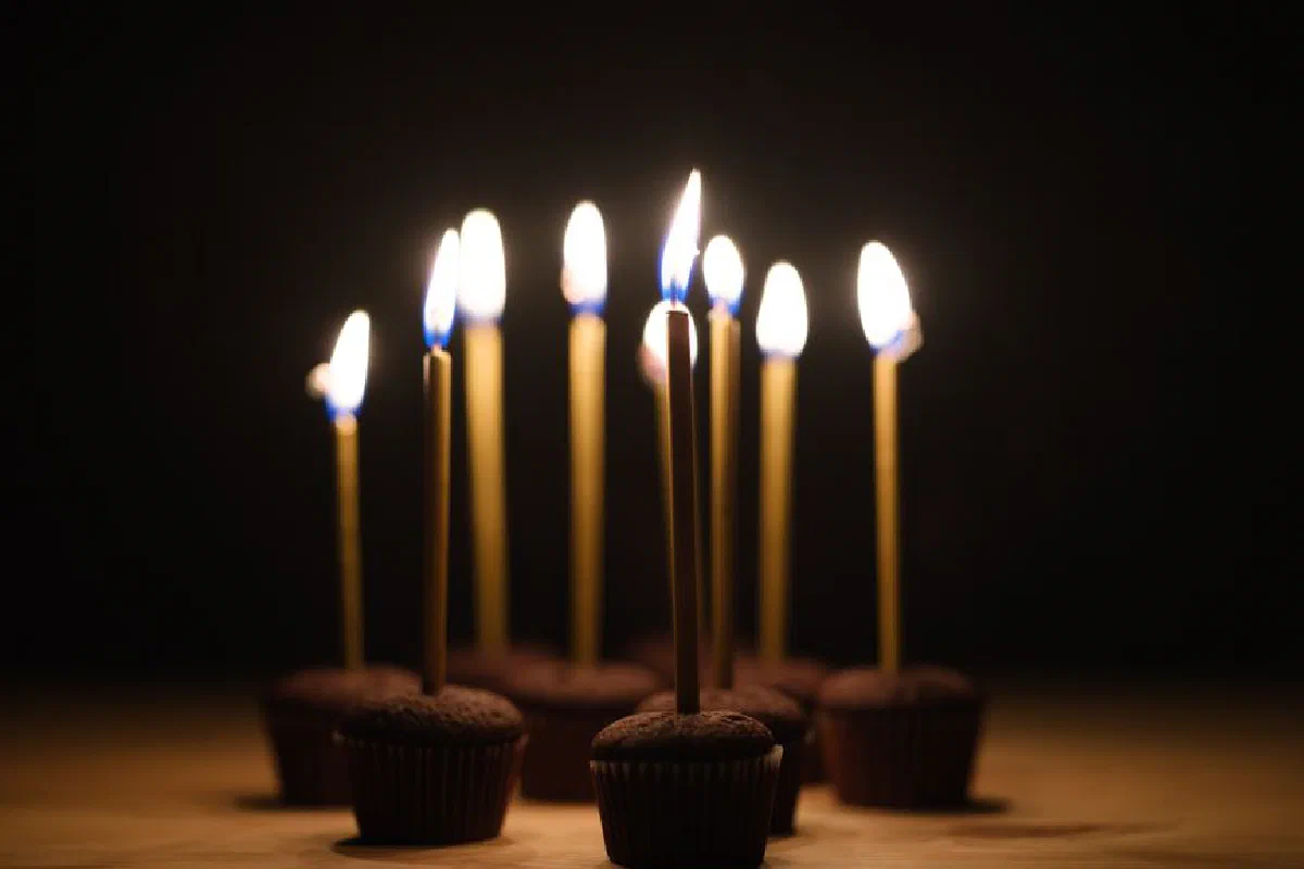 Chocolate cupcakes with flaming candles against a dark backdrop, ideal for celebration themes.