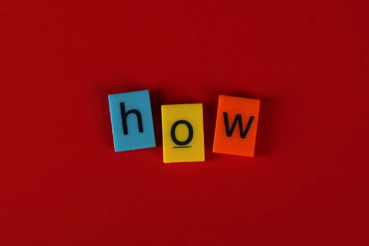 Colorful letter tiles spelling 'How' on a vibrant red background, ideal for educational content.