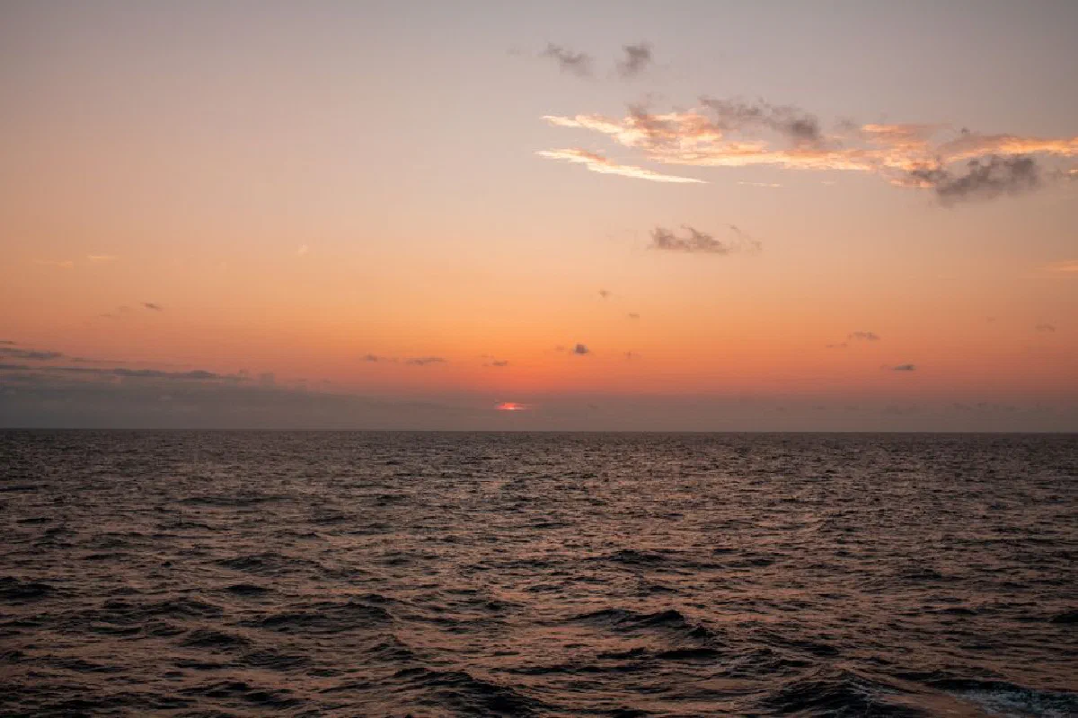 Peaceful ocean sunset capturing vibrant orange hues and gentle waves.