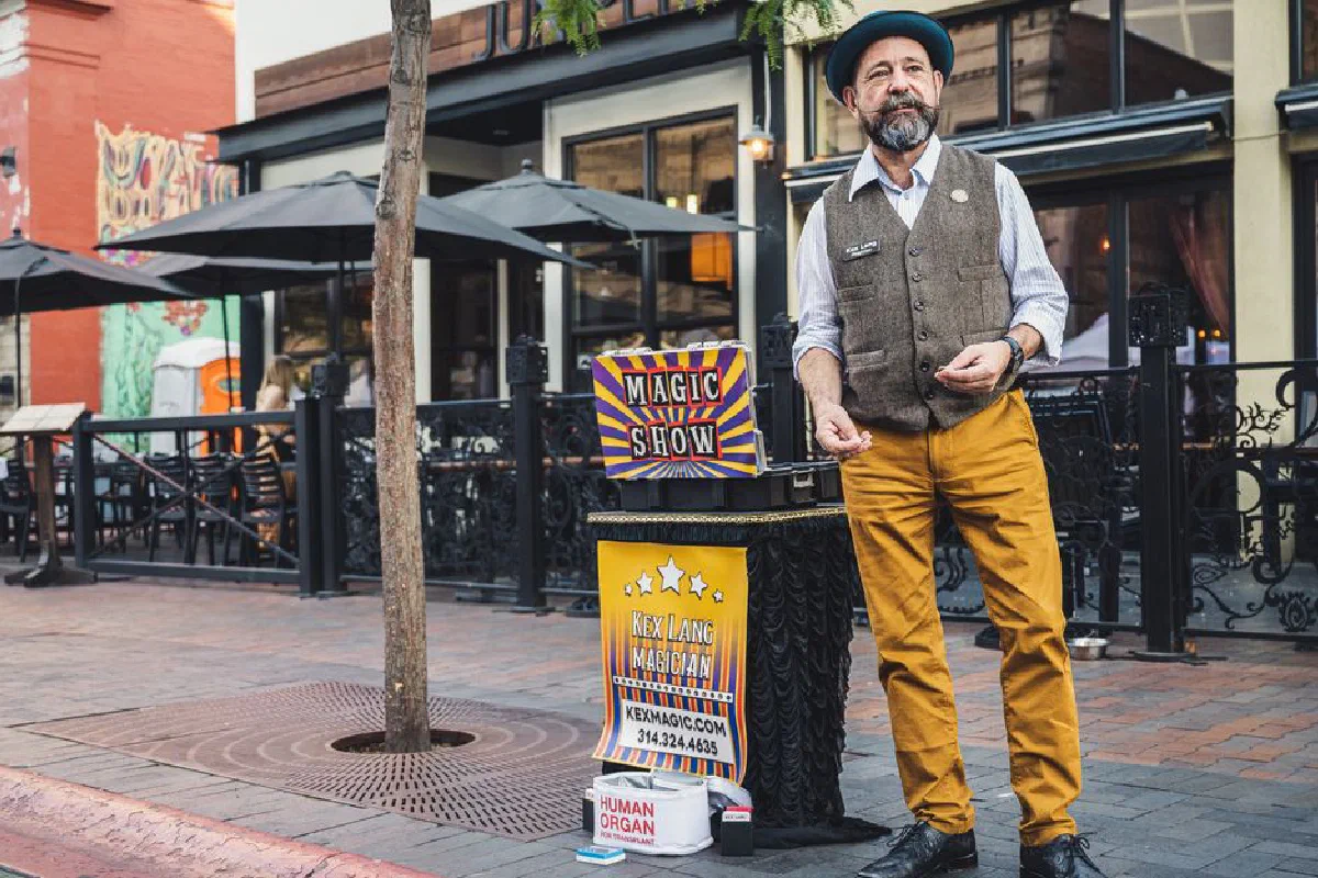 Street magician performing a magic show in an urban outdoor setting.
