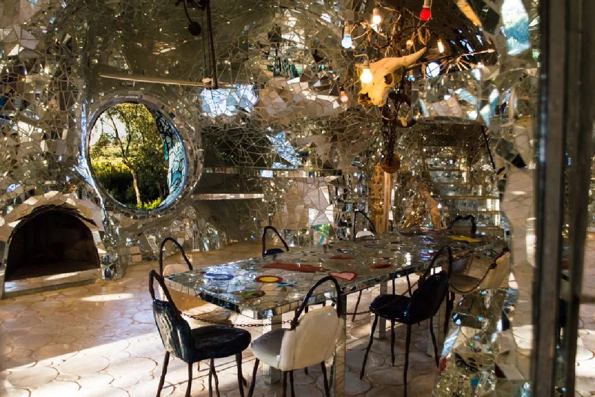 Unique dining room with mosaic mirrors and eclectic decor, featuring a central table and chairs.