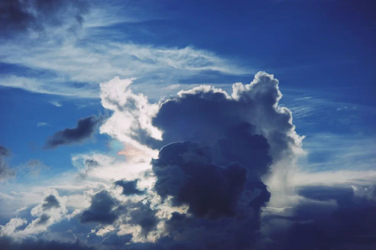 Dramatic cloudscape with vibrant blue sky and sunlight breaking through, showcasing dynamic weather patterns.