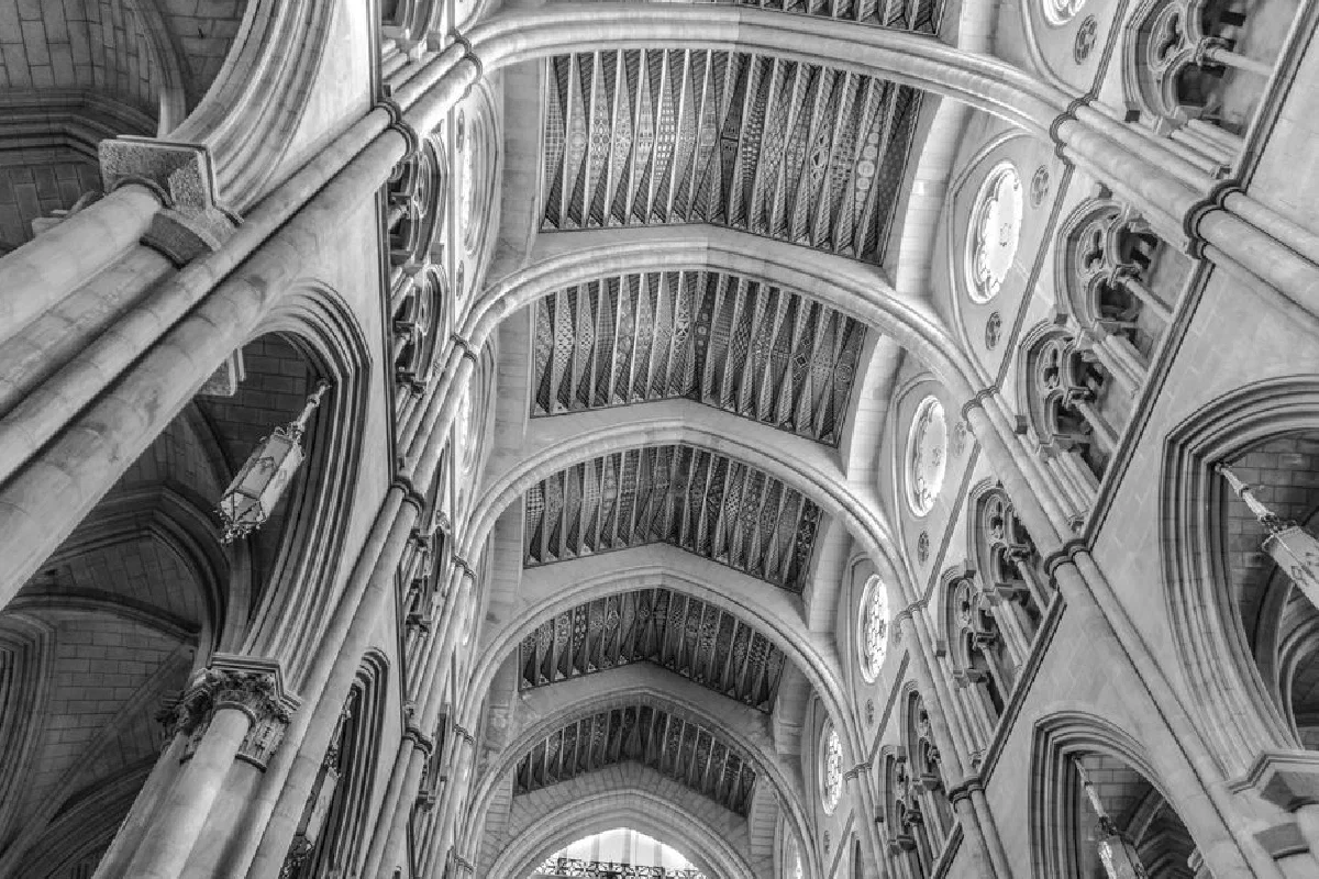 Black and white interior shot of a gothic cathedral with ornate arches and columns.