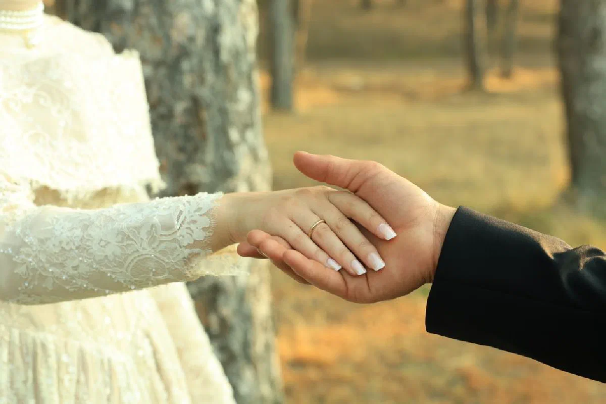 Close-up of a couple holding hands in a romantic outdoor setting, symbolizing love and commitment.