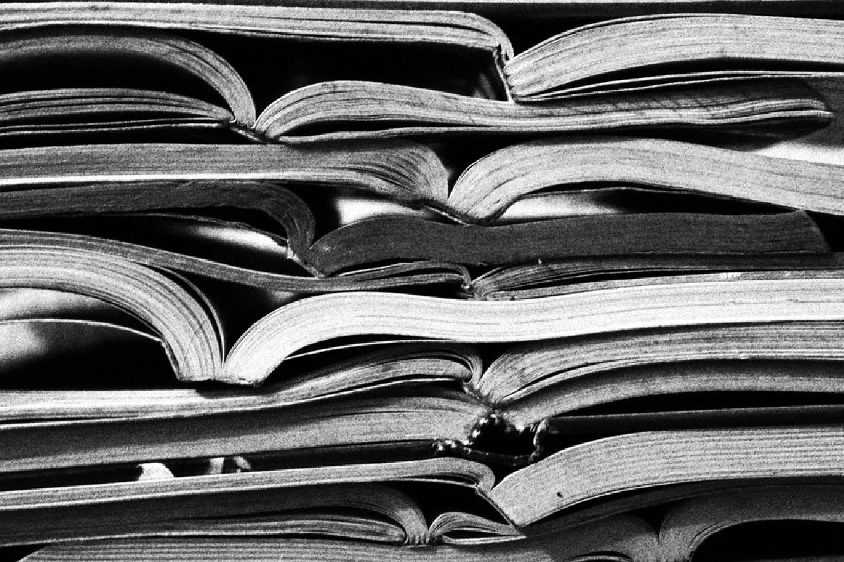 Monochrome image of stacked open books, showcasing texture and patterns in literature.