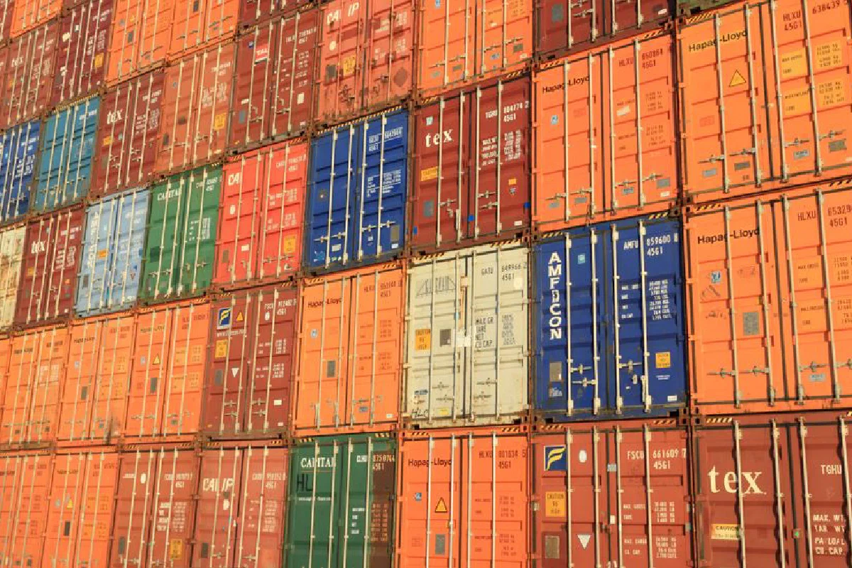 Colorful shipping containers stacked in a harbor, symbolizing global trade.