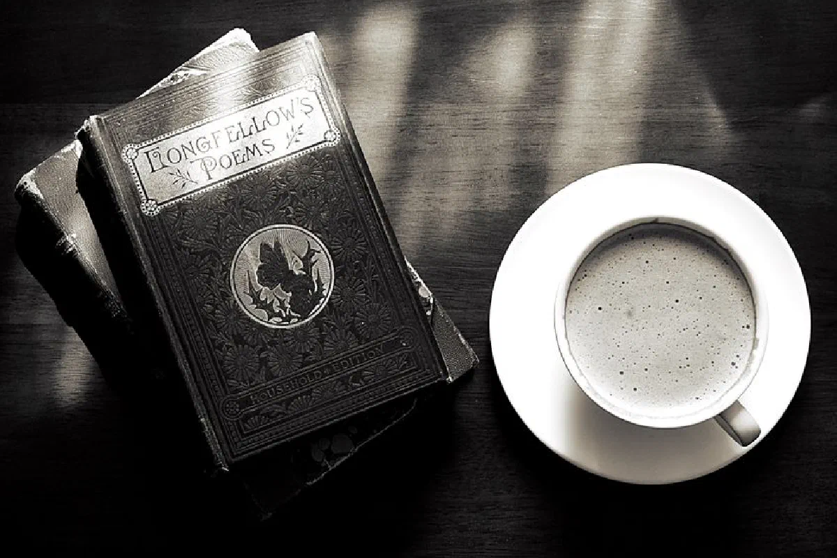A captivating vintage still life of a coffee cup and Longfellow's poems book