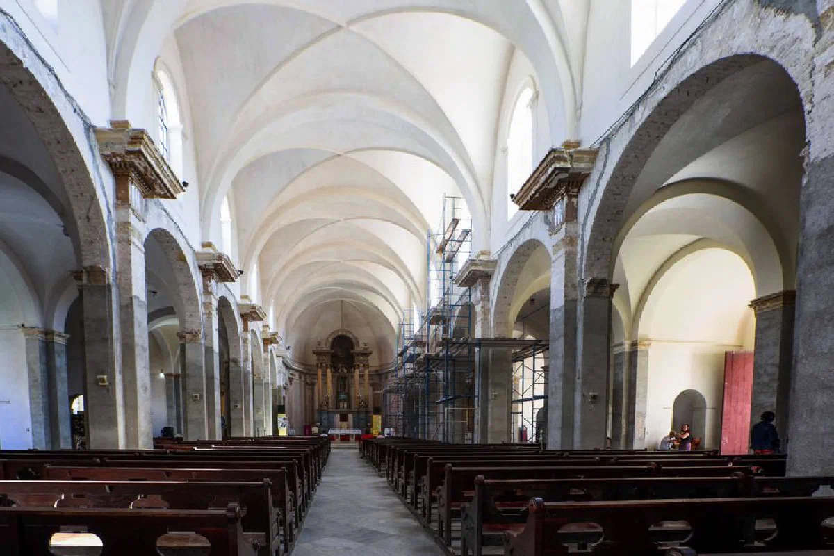 Spacious church interior with scaffolding, pillars, and pews under renovation.