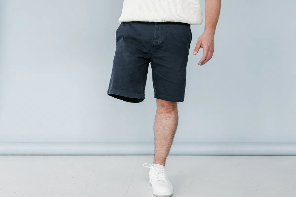 Young male amputee in casual attire standing indoors against a light background.