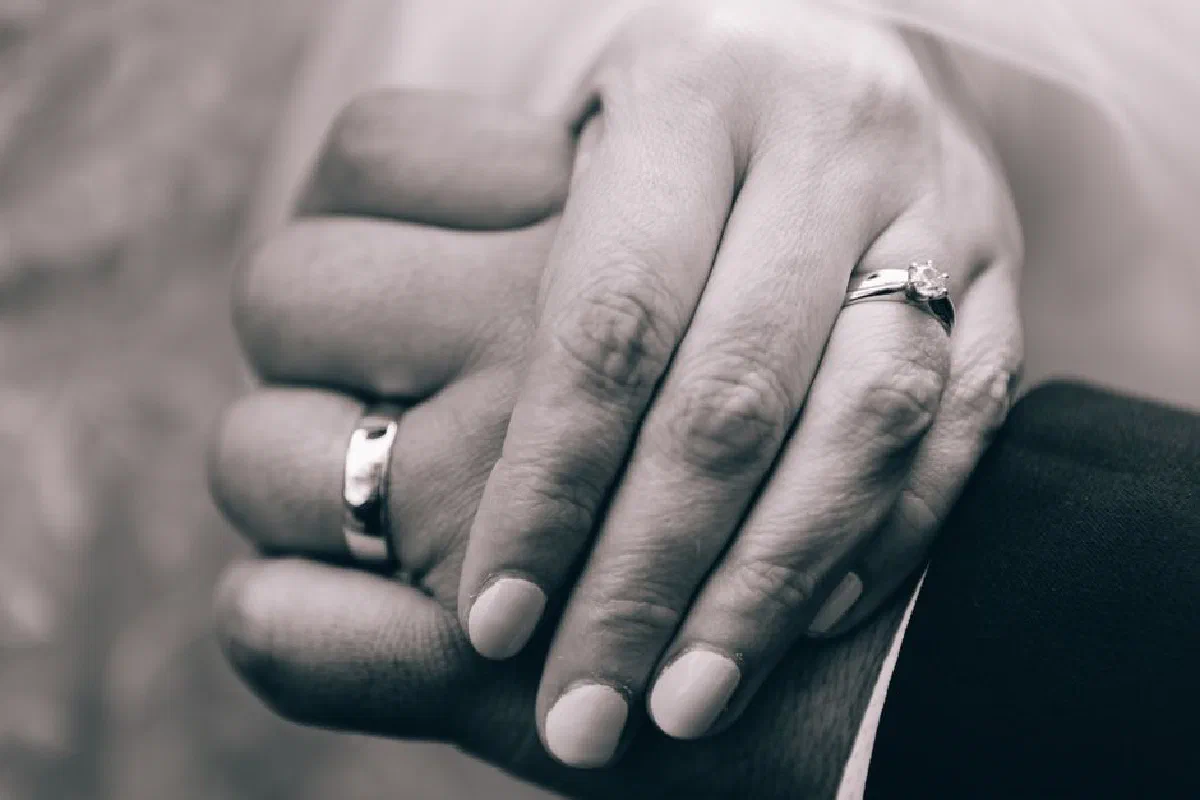 Close-up of bride and groom's hands showcasing wedding rings in an intimate embrace.
