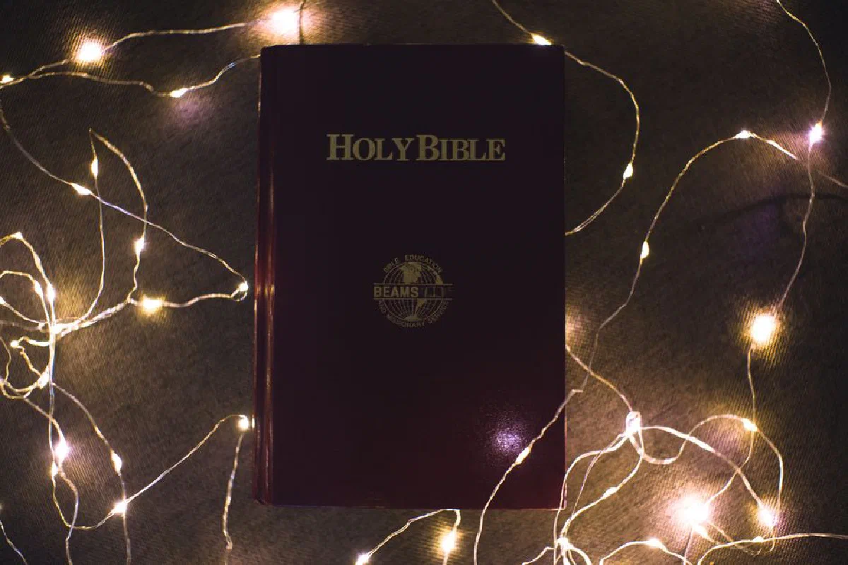Holy Bible surrounded by glowing Christmas lights in a warm, sacred setting.