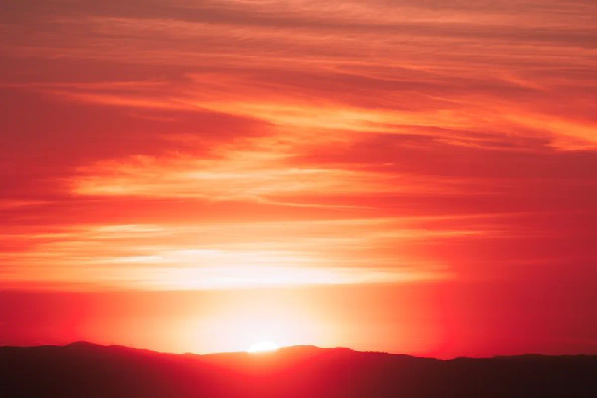 A breathtaking scene of a vibrant sunset casting warm hues over distant mountains.