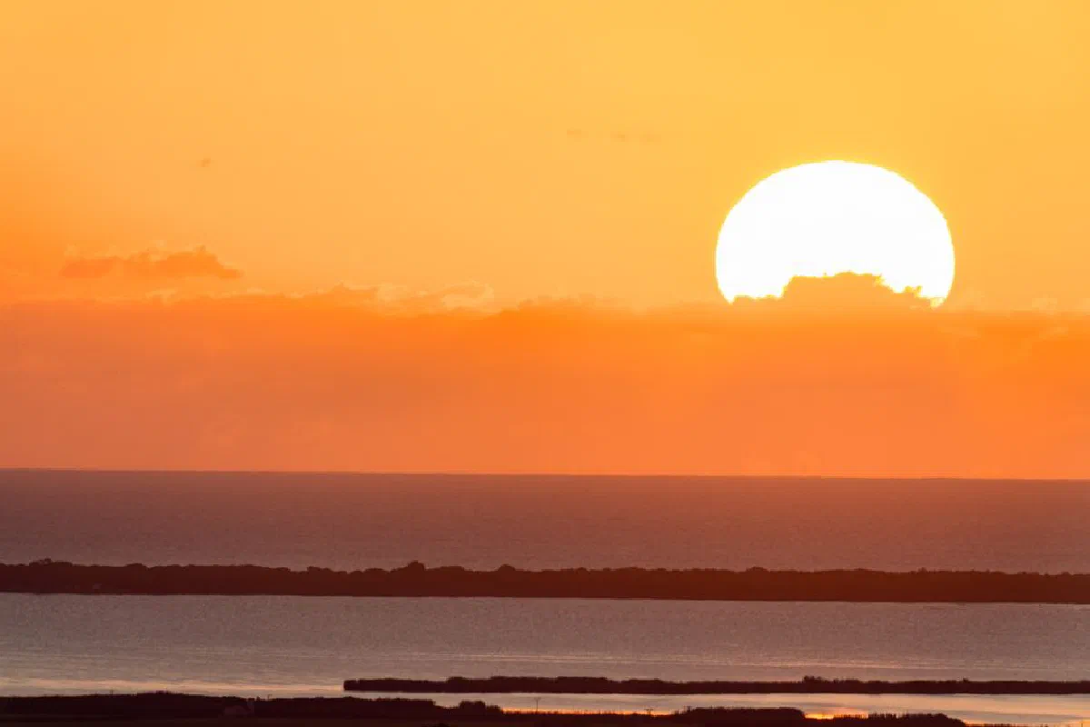 Captivating sunrise with vibrant orange hues reflecting over the calm sea in Valencia, Spain.