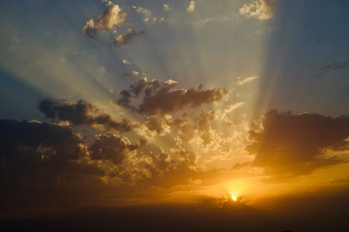 A breathtaking sunset with sunbeams piercing through clouds, creating a dramatic sky.