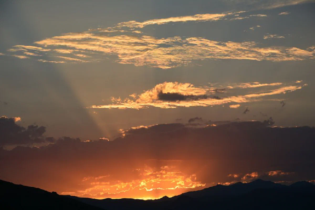 Captivating sunset with dramatic clouds and glowing sky over a mountain range.
