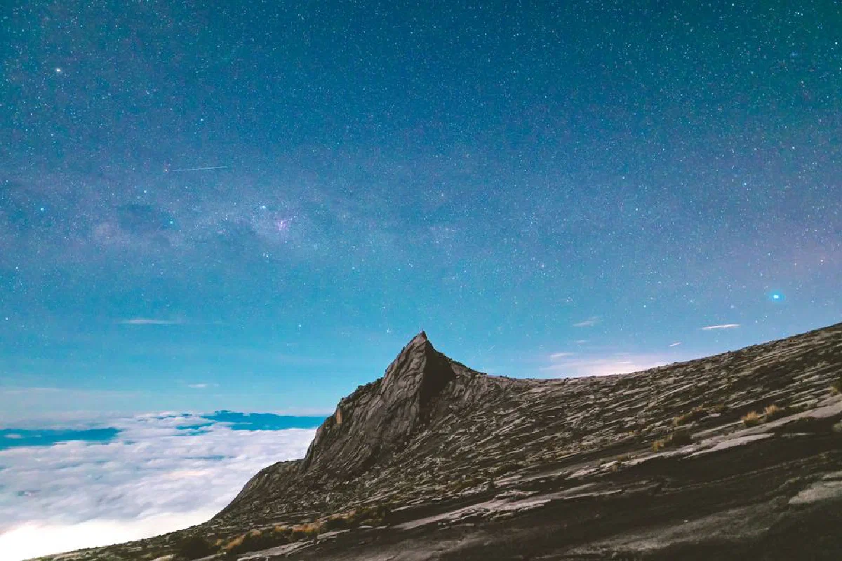 Capture the magic of Mount Kinabalu's peak against a vibrant night sky filled with stars.
