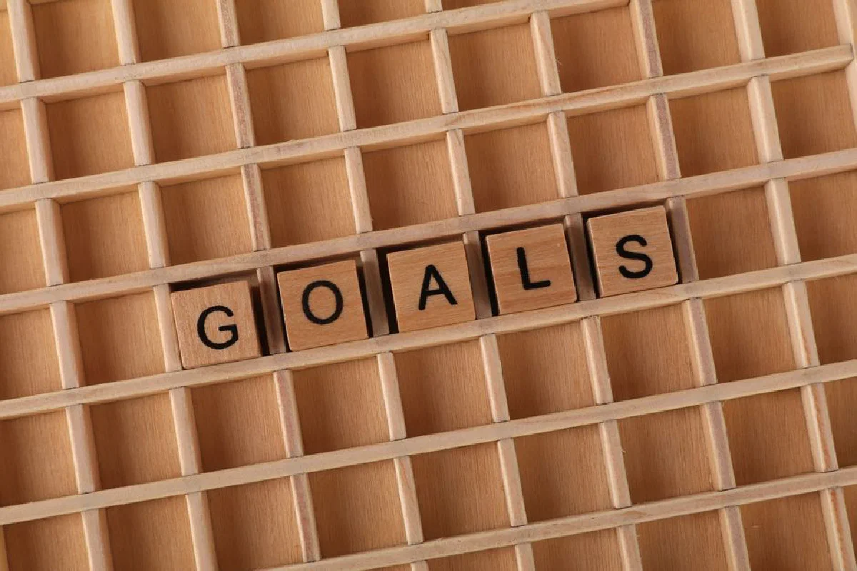 Wooden blocks spelling the word 'Goals' arranged on a wooden grid, symbolizing planning and achievement.