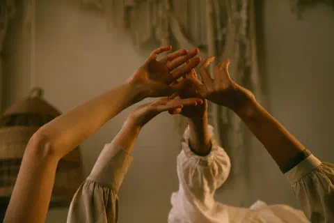 An artistic composition of three raised hands with soft focus and warm tones in an indoor setting.